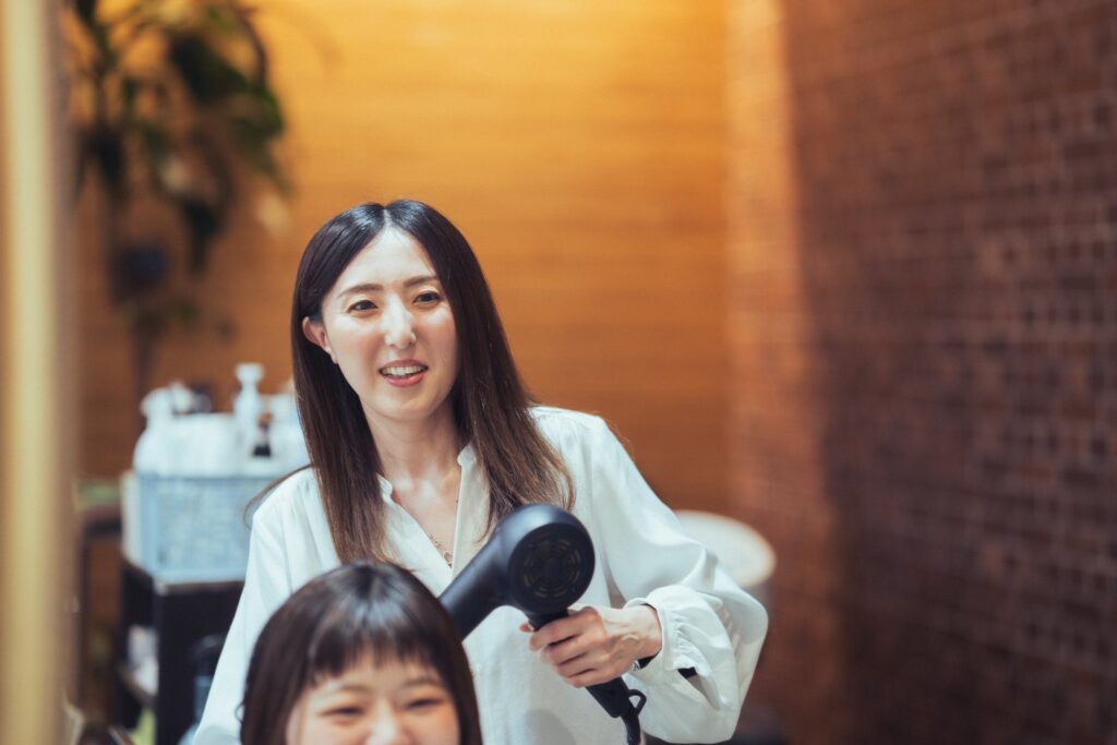 女性スタッフがドライヤーで髪を乾かしている写真